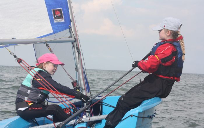 Two girls sailing a Hartely dinghy on the sea.