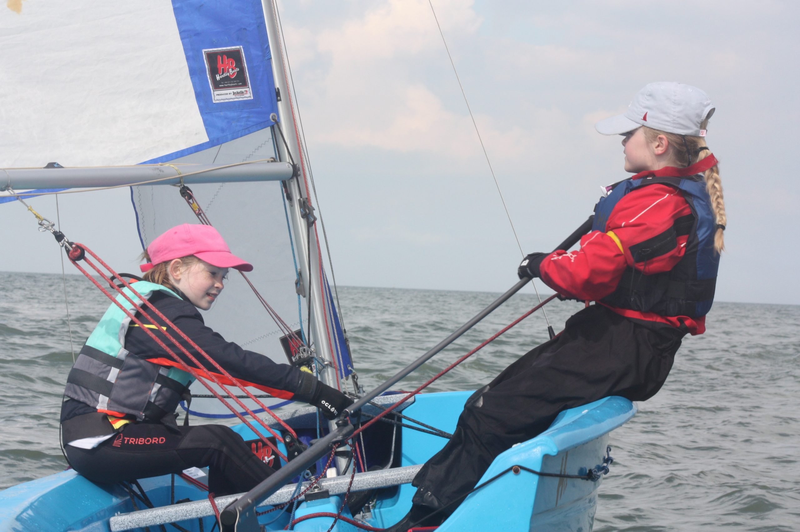 Two girls sailing a Hartely dinghy on the sea.